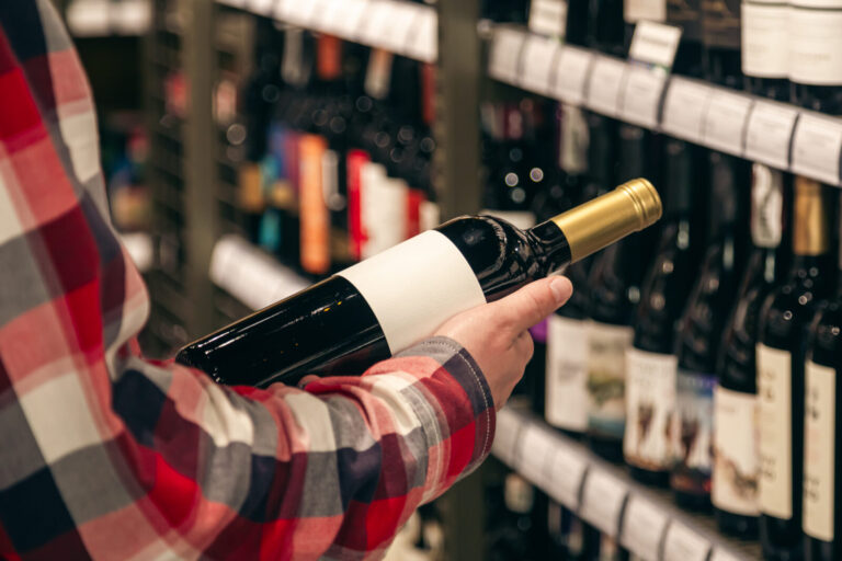 A male customer holding a bottle of red wine, close up